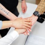 Close-up of a diverse team stacking hands on an office desk, symbolizing teamwork.