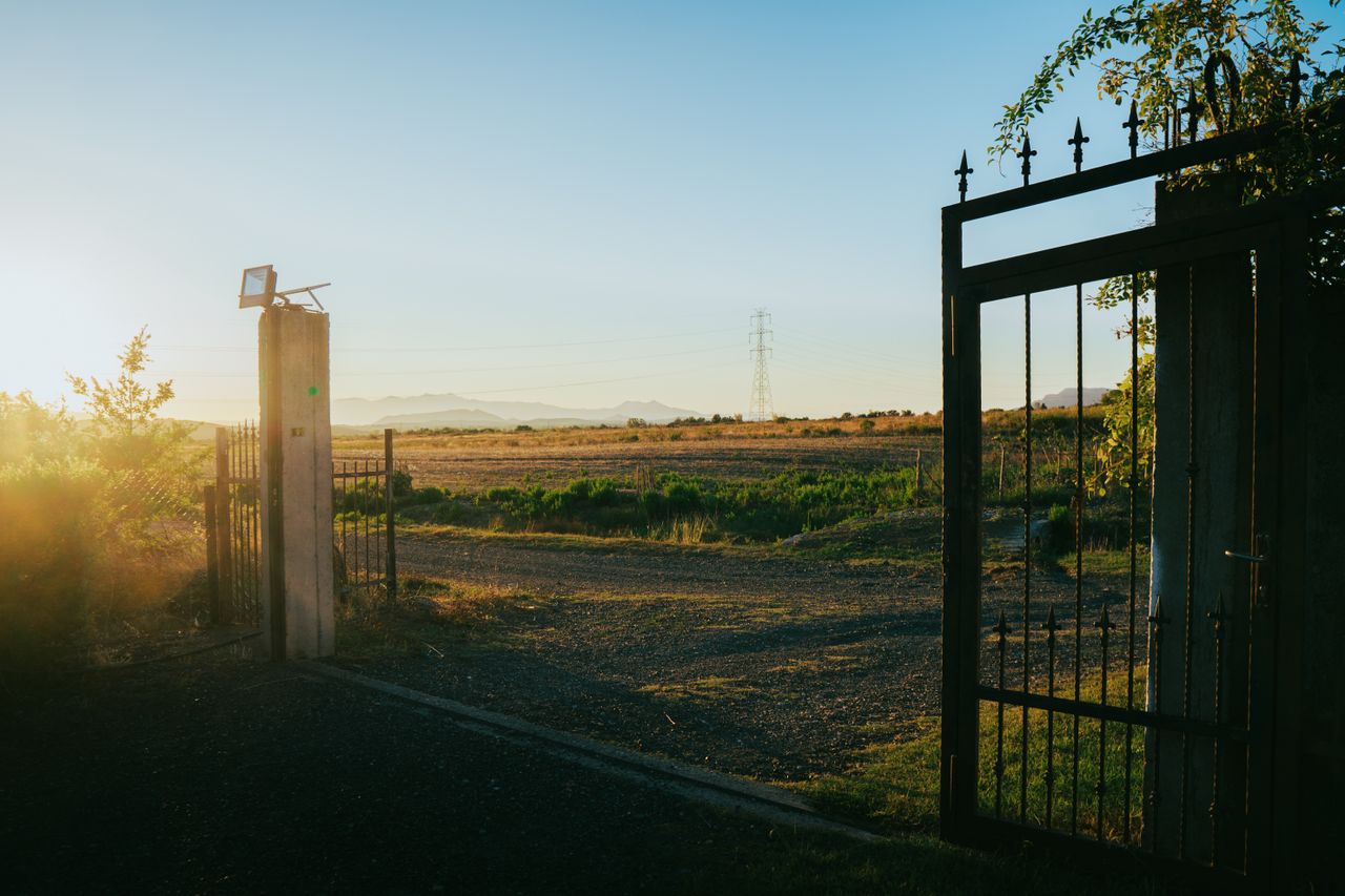 Serene sunset view through an open gate in Fishtë, showcasing the tranquil Albanian countryside.