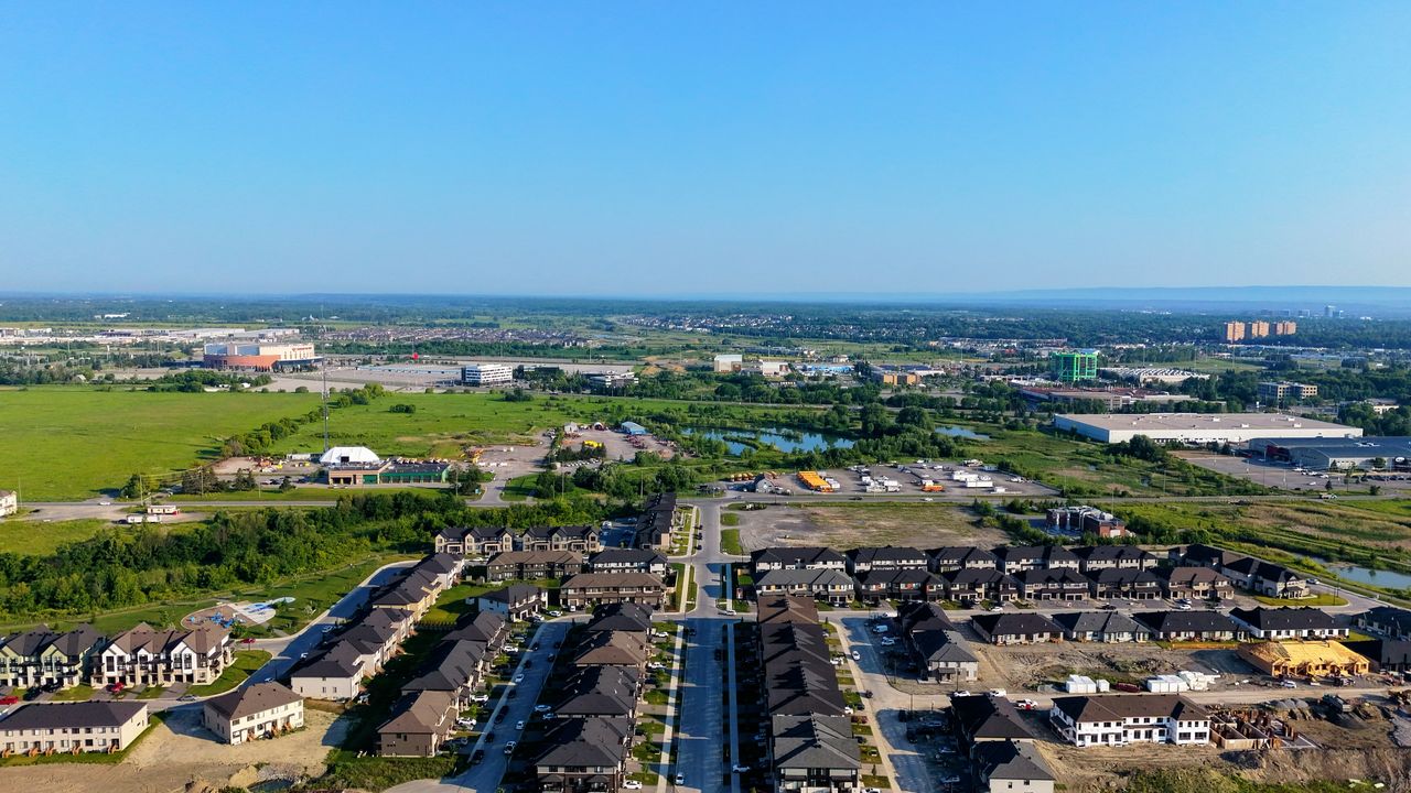 Aerial view of suburban housing and industrial areas under clear blue skies.
