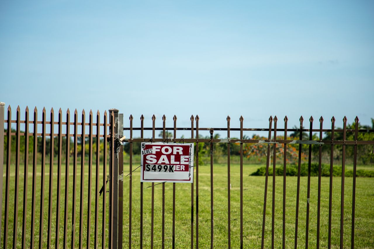 Careers A large plot of land bordered by an iron fence, complete with a 'For Sale' sign in Miami, FL. Ideal for development.